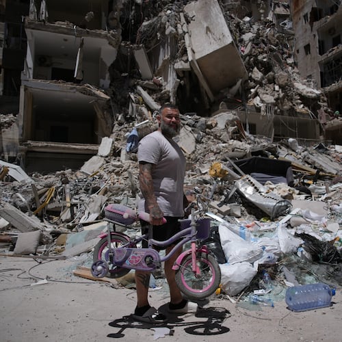 Barber Wissam Srour, 41, holds his daughter's bicycle recovered from his barbershop as he searches for belongings in the rubble of the shop, damaged in an Israeli strike, in the southern port city of Tyre, Lebanon, Friday, June 19, 2026. (AP Photo/Hassan Ammar)