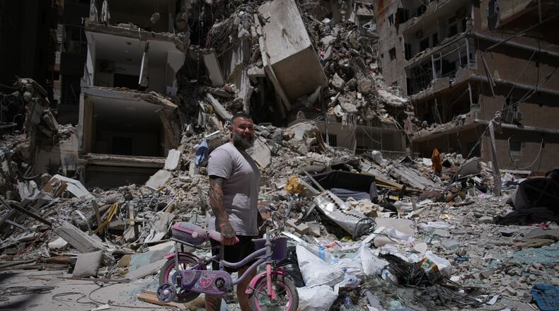 Barber Wissam Srour, 41, holds his daughter's bicycle recovered from his barbershop as he searches for belongings in the rubble of the shop, damaged in an Israeli strike, in the southern port city of Tyre, Lebanon, Friday, June 19, 2026. (AP Photo/Hassan Ammar)