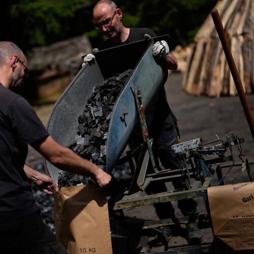 Brothers Immo and Sascha Feldmer put charcoal into paper bags after weighing it at their traditional production site near Hasselfelde in Germany's Harz, Germany, Thursday, June 18, 2026. (AP Photo/Matthias Schrader)