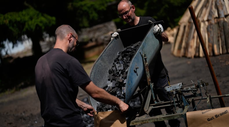 Brothers Immo and Sascha Feldmer put charcoal into paper bags after weighing it at their traditional production site near Hasselfelde in Germany's Harz, Germany, Thursday, June 18, 2026. (AP Photo/Matthias Schrader)