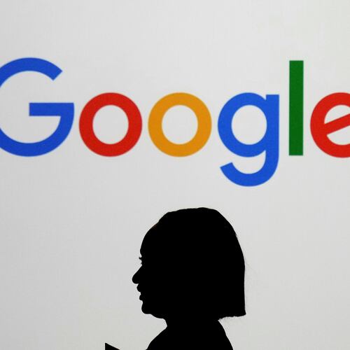 FILE - A woman walks by a giant screen with a logo at an event at the Paris Google Lab on the sidelines of the AI Action Summit in Paris, on Feb. 9, 2025. (AP Photo/Thibault Camus,File)