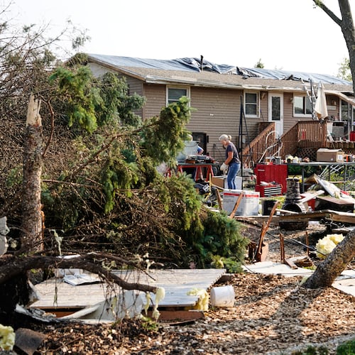 People clean up debris in front of a damaged home after a tornado struck the day before, Tuesday, July 28, 2026, in Appleton, Wis. (AP Photo/Kayla Wolf)