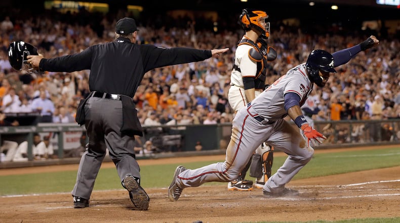 Atlanta Braves' Jason Heyward, right, celebrates after being called safe at home by umpire Ed Hickox, left, in front of San Francisco Giants catcher Buster Posey during the sixth inning of a baseball game in San Francisco, Tuesday, May 13, 2014. Giants manager Bruce Bochy challenged the ruling but the play stood. (AP Photo)