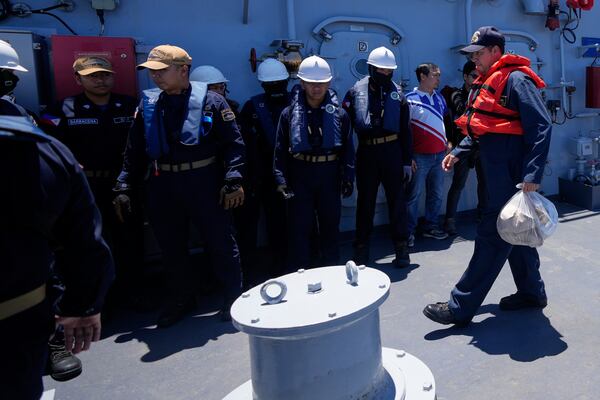 A US Navy personnel, right, prepares to be transferred by to USS Shoup (DDG86) as he walks past Filipinos on board the Philippine Navy Ship BRP Jose Rizal during the Philippines United States Japan Multilateral Maritime Cooperative Activity off a disputed South China Sea shoal on Friday, March 28, 2025. (AP Photo/Aaron Favila)