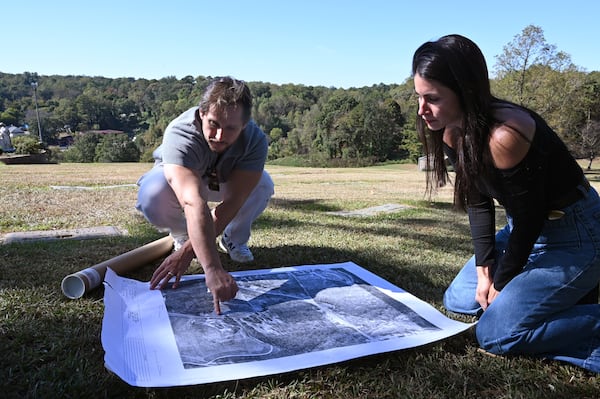 Tim Amoui, and his wife Shayda Frost, owners of Hollywood Cemetery, show a map of Hollywood Cemetery site, with the actual Hollywood Cemetery in the background, Friday, Oct. 24, 2025, in Atlanta. (Hyosub Shin/AJC)
