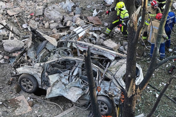 A destroyed car is seen as firefighters work on the site of a damaged building after a Russian attack in Kyiv, Ukraine, early Monday, June 23, 2025. (AP Photo/Efrem Lukatsky)