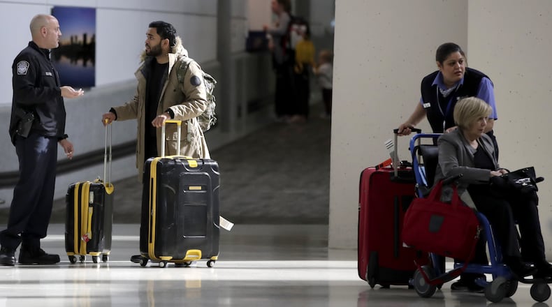 A traveler, second from left, talks to a U.S. Customs and Border Protection official near the exit of the international arrivals terminal at Newark Liberty International Airport, Thursday, Oct. 26, 2017, in Newark, N.J. . Long-haul carriers are starting new screening procedures for U.S.-bound passengers after receiving new security guidelines from American authorities. (AP Photo/Julio Cortez)
