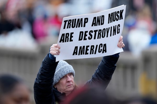 A person holds a sign at a rally supporting federal workers outside the IRS regional office Saturday, March 15, 2025, in Kansas City, Mo. (AP Photo/Charlie Riedel)