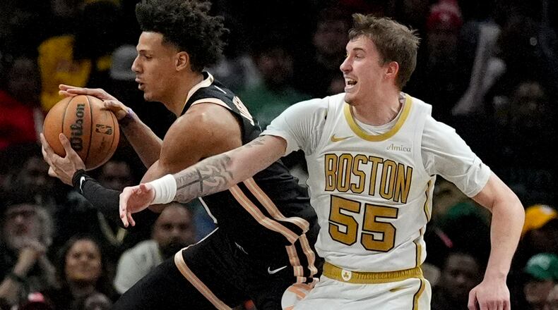 Atlanta Hawks forward Jalen Johnson (1) takes a rebound against Boston Celtics guard Baylor Scheierman (55) during the first half of an NBA basketball game, Saturday, Jan. 17, 2026, in Atlanta. (AP Photo/Mike Stewart)