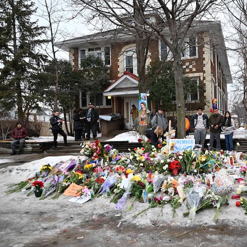 People gather around a makeshift memorial honoring Renee Good who was fatally shot by a federal law enforcement agent near the site of the shooting in Minneapolis, Thursday, Jan. 8, 2026. (AP Photo/Tom Baker)