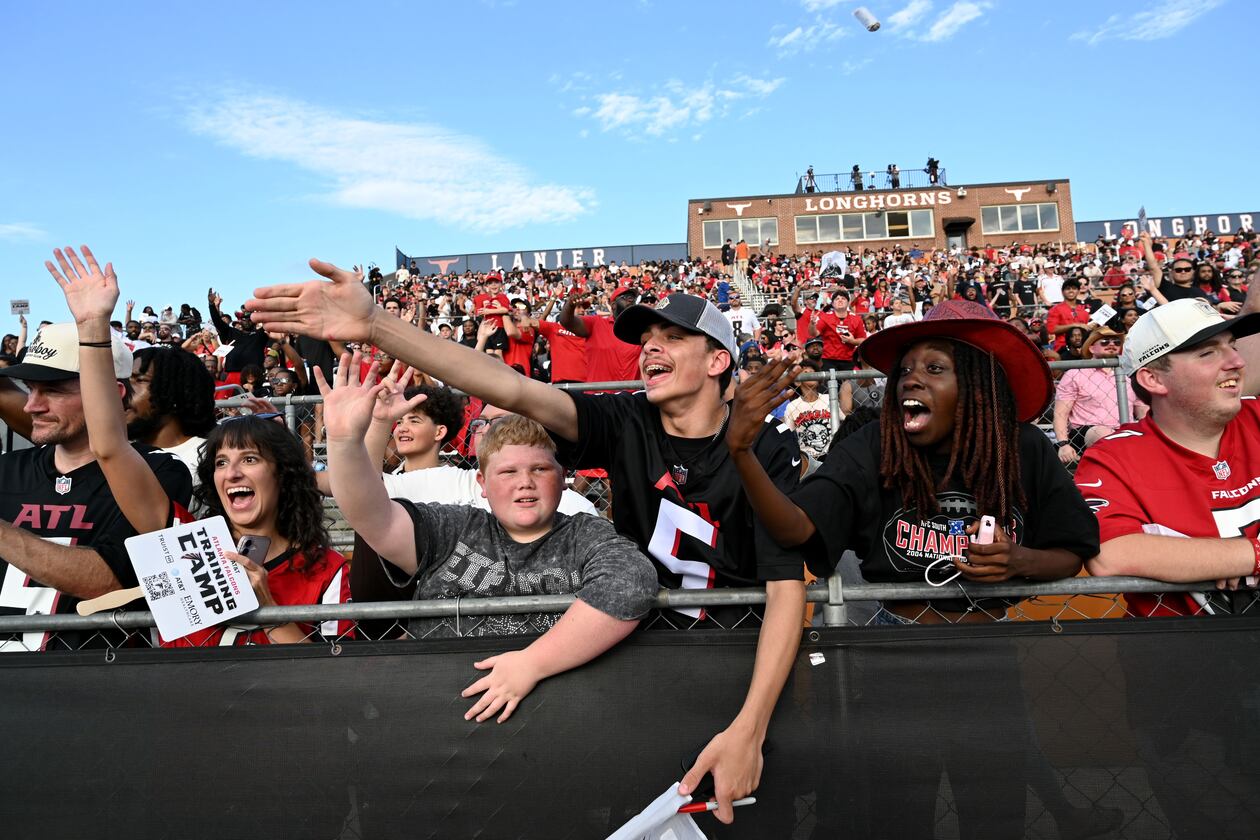 Football fans cheer as they watch their favorite players in action during the Atlanta Falcons' "Saturday Night Lights" practice Saturday, Aug. 8, 2026, at Lanier High School in Sugar Hill. (Hyosub Shin/AJC)