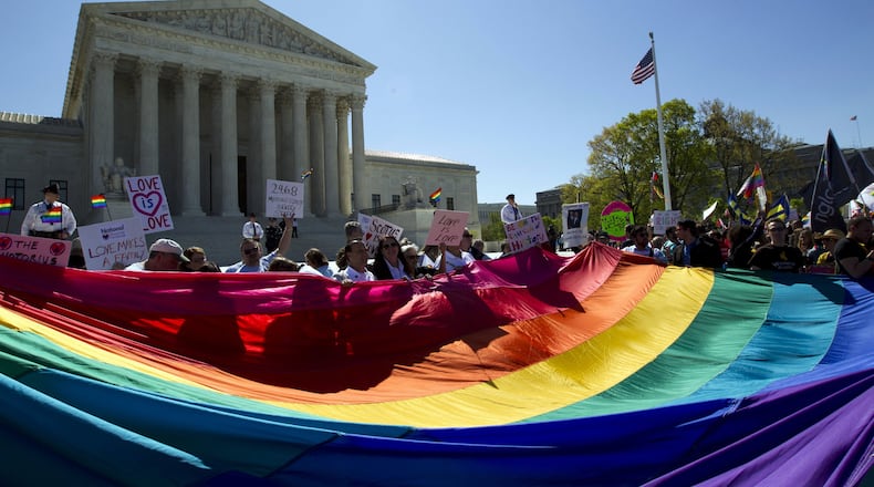 In this April 28, 2015 file photo, demonstrators stand in front of a rainbow flag of the Supreme Court in Washington. (AP Photo/Jose Luis Magana, File)