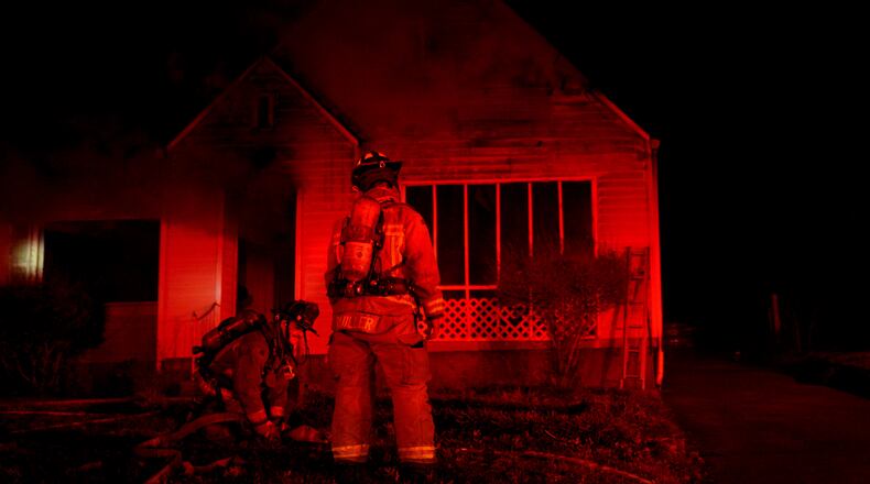 An Atlanta firefighter drags a hose line to a burning home late Friday evening.