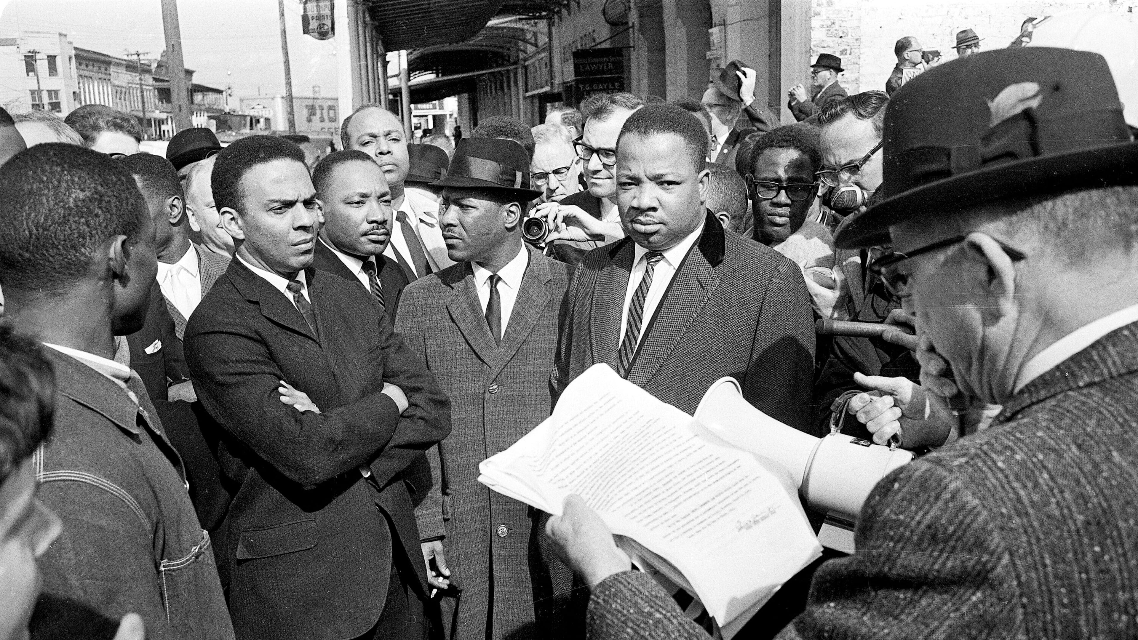 FILE - A federal marshal reads a court order halting a planned voter registration protest as Dr. Martin Luther King Jr., right, and fellow marcher Andrew Young, left, look on in Selma, Ala., March 9, 1965. (AP Photo, File)