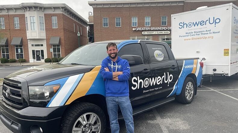 John Lynn, a ShowerUp volunteer, poses with a shower truck and trailer. Lynn is part of a nonprofit network that offers shower services to people living on the streets of Chattanooga, TN. (Photo Courtesy of Mark Kennedy)