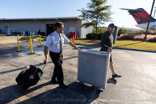 Delta pilot Richard Baker rolls his newly purchased galley cart from the Delta Flight Museum Surplus Sale in Atlanta on Friday, Oct. 10, 2025. He plans to use it in a building he is renovating at his home in Florida, which already has a Boeing 747 lavatory door serving as its restroom door. (Arvin Temkar/AJC)