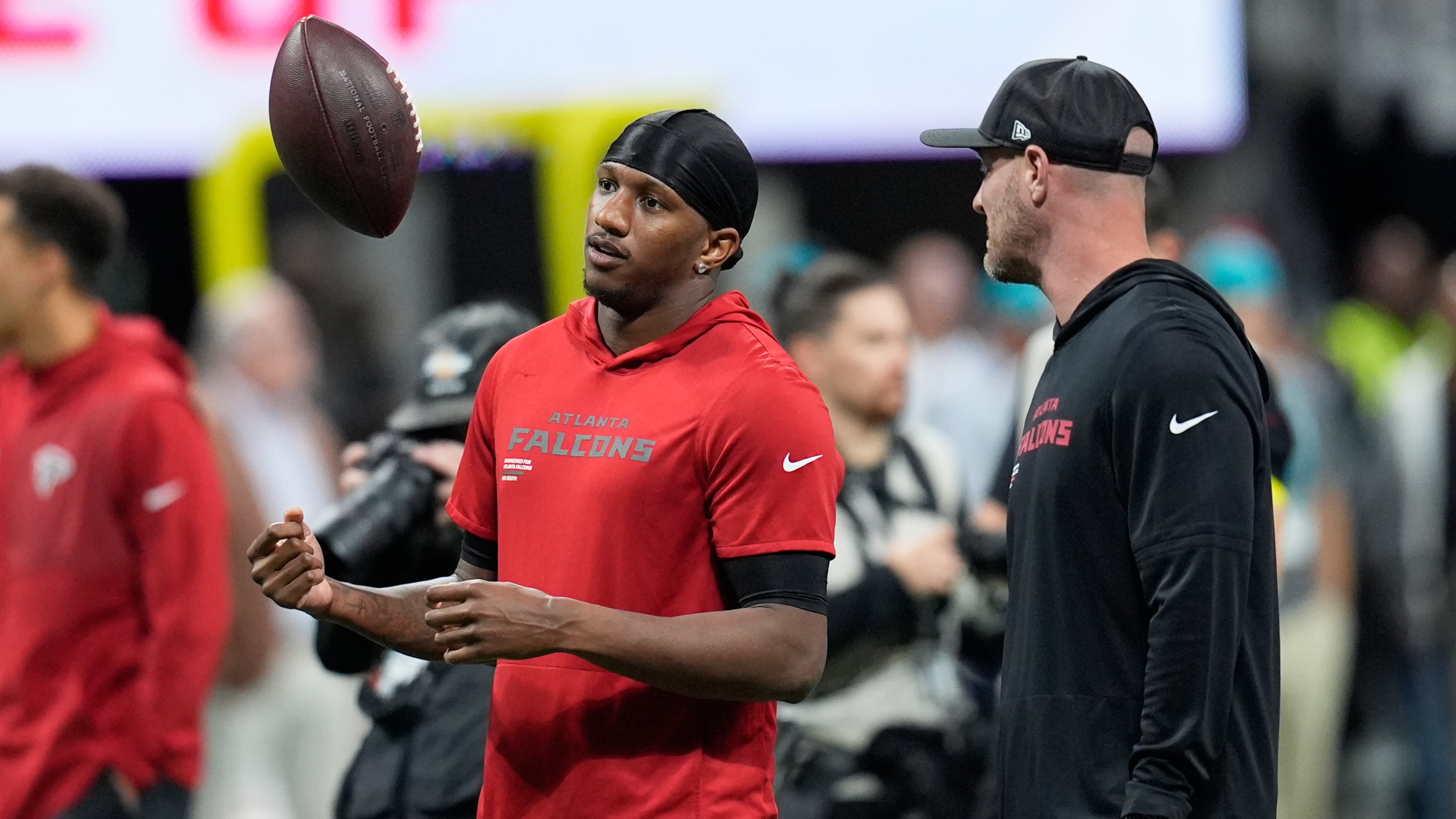 Atlanta Falcons quarterback Michael Penix Jr., left, tosses a football before an NFL football game against the Miami Dolphins, Sunday, Oct. 26, 2025, in Atlanta. (AP Photo/Mike Stewart)