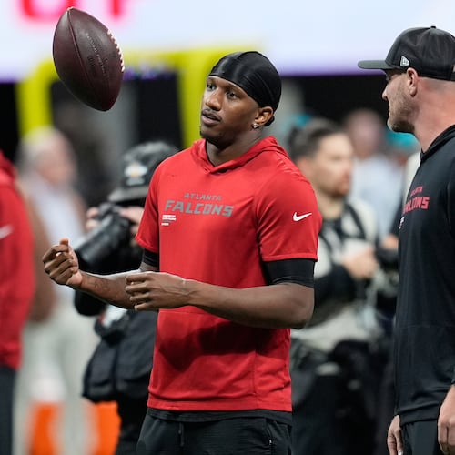 Atlanta Falcons quarterback Michael Penix Jr., left, tosses a football before an NFL football game against the Miami Dolphins, Sunday, Oct. 26, 2025, in Atlanta. (AP Photo/Mike Stewart)