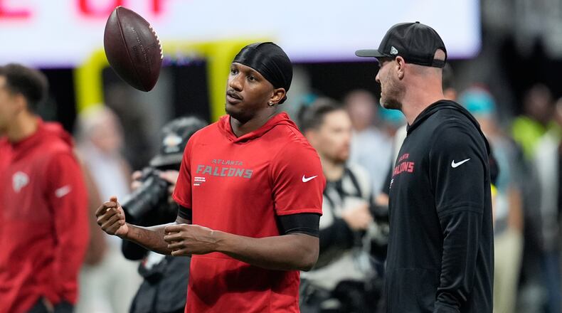 Atlanta Falcons quarterback Michael Penix Jr., left, tosses a football before an NFL football game against the Miami Dolphins, Sunday, Oct. 26, 2025, in Atlanta. (AP Photo/Mike Stewart)