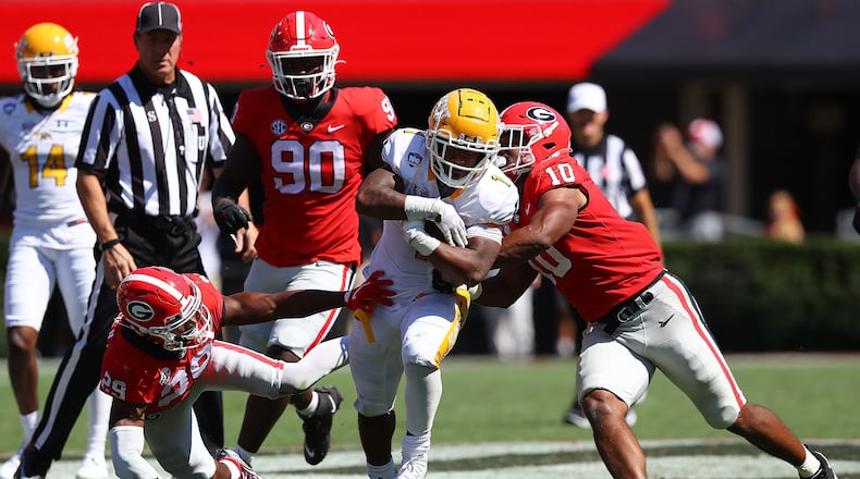 Kent State running back Marquez Cooper picks up a first down and is tackled by Georgia defensive back Christopher Smith (left) and linebacker Jamon Dumas-Johnson on a scoring drive during the fourth quarter Saturday in Athens. Cooper scored a touchdown later in the drive to keep the game close. (Curtis Compton / Curtis Compton@ajc.com)