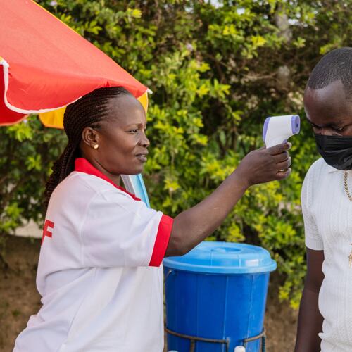A health worker uses a thermometer to screen a man by the roadside in Bunia, Congo, Tuesday, May 19, 2026. (AP Photo/Moses Sawasawa)