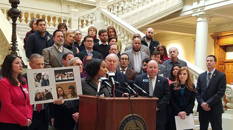 Fulton County Deputy District Attorney Fani Willis on Wednesday holds up images of victims of crimes that would have qualified under a bill state Rep. Meagan Hanson (front row, right) is proposing to create a hate crimes law. Maya T. Prabhu / maya.prabhu@ajc.com