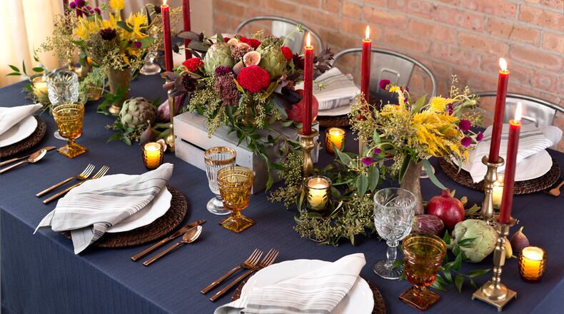 A mixture of fruits, vegetables and flowers create a lovely runners on this table. The woven chargers beneath the scalloped porcelain plates complement the organic accents on the table.