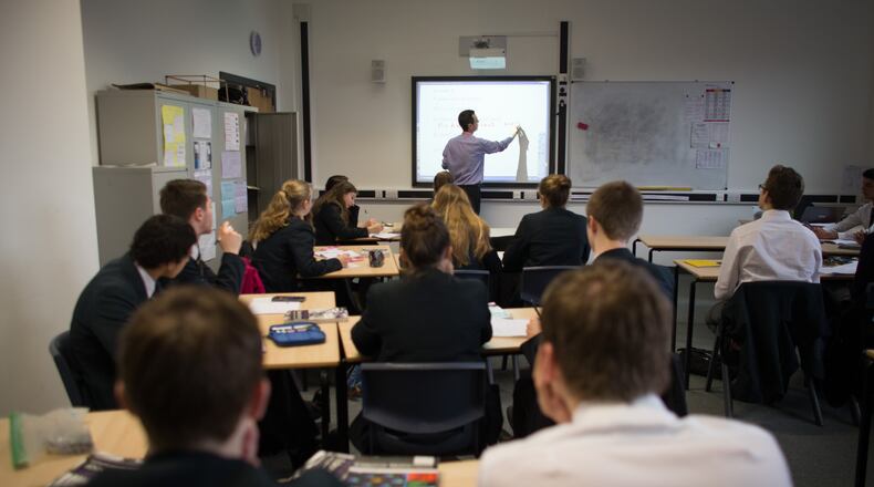 A teacher talks to students during a math lesson. (Photo by Matt Cardy/Getty Images)