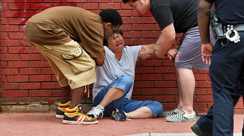 Michael Seagrave (left) and James Sung (right) help a grieving Chae Sung to her feet after she arrived at the store where her husband was killed in 2010. JOHN SPINK / JSPINK@AJC.COM
