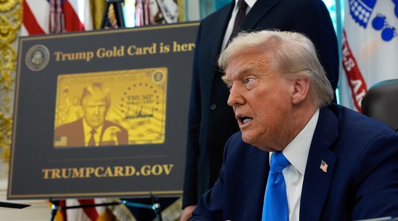 FILE - A poster showing the Trump Gold Card is seen as President Donald Trump signs executive orders in the Oval Office of the White House, Sept. 19, 2025, in Washington. (AP Photo/Alex Brandon, File)