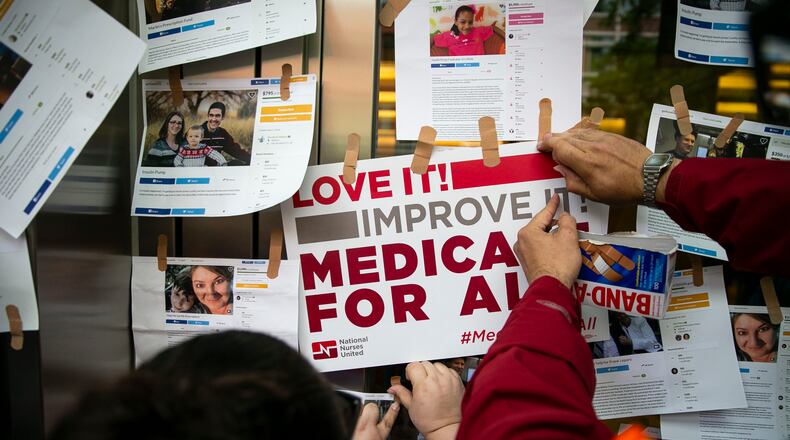 Examples of GoFundMe pages for patients who used crowdfunding to cover medical expenses are posted on doors for the headquarters of Pharmaceutical Research and Manufacturers of America during a “Medicare for All” rally in Washington, April 29, 2019. (Al Drago/The New York Times)