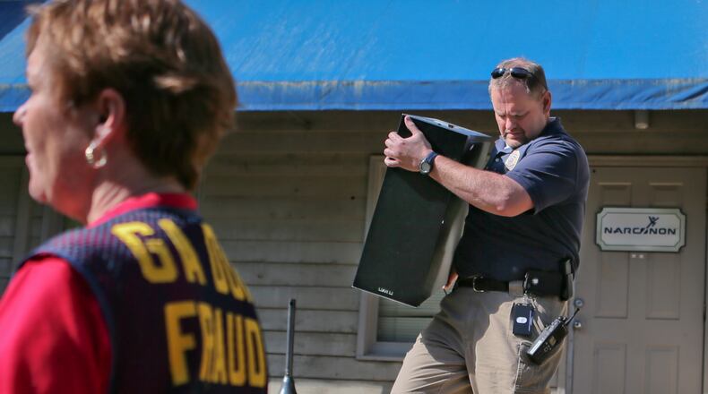 Georgia Insurance and Safety Fire Commissioner's Fraud Unit's chief investigator, Sherry Mowell (left) looks on as Gwinnett County D.A. Office investigator, Roy Mangrum (right) brings out another computer from Narconon of Georgia offices as authorities served a search warrant on Friday, April 26, 2013.