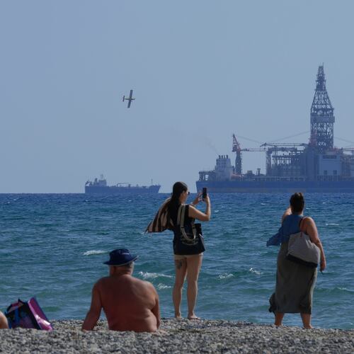 FILE - People on the beach take photos of the 'Tungsten Explorer' drilling ship, in the southern coastal city of Larnaca, Cyprus, Wednesday, Nov. 3, 2021. (AP Photo/Petros Karadjias, File)