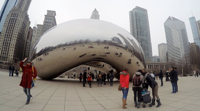 Tourists have fun taking photos of the Cloud Gate, also known as the Bean, in Millennium Park in Chicago's vibrant downtown.