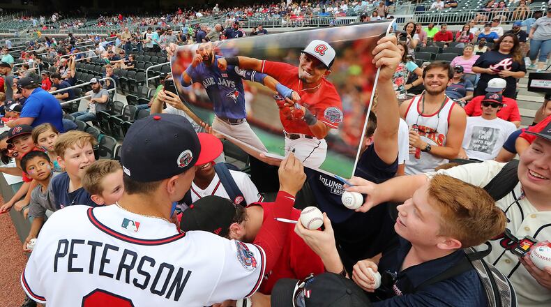 Braves' Jace Peterson signs a poster displayed by fans with his face superimposed on a poster hitting Blue Jays' Jose Bautista.