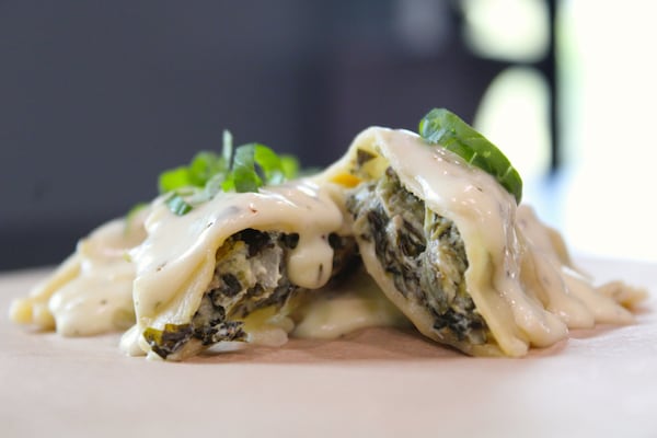 A close-up shot of a saucy ravioli, cut in half to show creamed spinach.