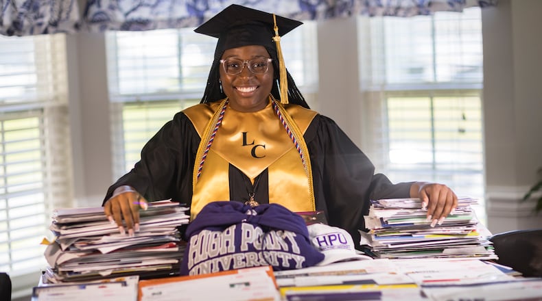 Liberty County High School graduate Madison Crowell, who has received college scholarship offers totaling more than $14 million, poses with some of the offers laid out on her family's dining room table on Wednesday, May 29, 2024 in Hinesville, Georgia. (AJC Photo/Stephen B. Morton)