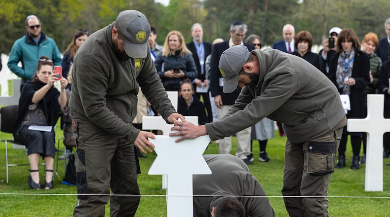 Workers replace a cross with a Star of David at a military cemetery. (Photo courtesy of Operation Benjamin)