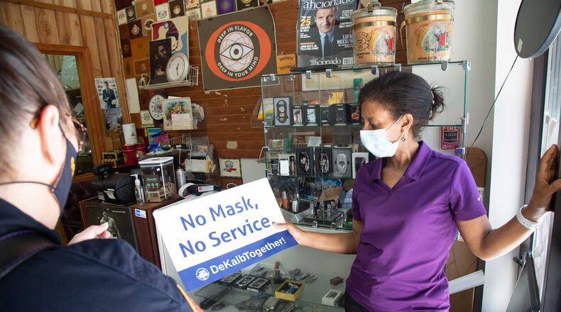 Paramedic with Dekalb Fire Rescue Stephanie Jordan Gives Rukia Lema, a pack of masks, and No Mask, No Service signs at the Got Cigars shop in Decatur Saturday 25, 2020.  STEVE SCHAEFER FOR THE ATLANTA JOURNAL-CONSTITUTION