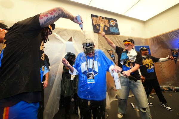 Clay Bennett, center, chairman the ownership group of the Oklahoma City Thunder, celebrates with players in the locker room after winning the NBA basketball championship with a Game 7 victory against the Indiana Pacers Sunday, June 22, 2025, in Oklahoma City. (AP Photo/Julio Cortez)