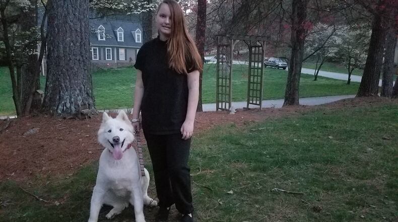 Young author Emily Rose Ross outside her east Cobb home with Balta, the family’s German Shepherd-husky rescue. Her first book, the sci-fi fantasy novel “Blue’s Prophecy,” will be released in May. CONTRIBUTED BY DIANE LORE