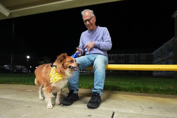 Carmine, of Waretown, and his dog Amber sit outside an evacuation center at Southern Regional High School during wildfires on Tuesday, April 22, 2025, near Stafford Township, N.J. (AP Photo/Chris Szagola)