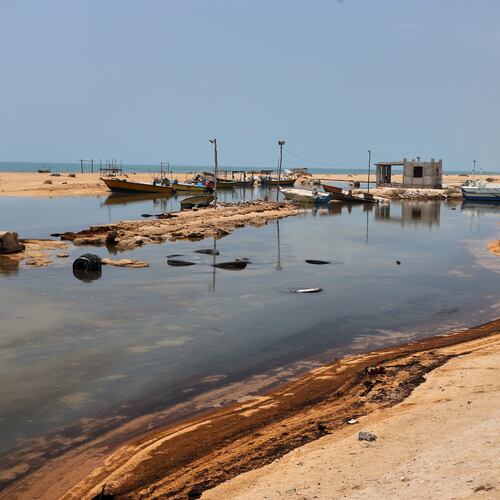 Oil residue lines the shore near fishing boats on Qeshm Island, Iran, Thursday, Aug. 13, 2026, amid ongoing wartime attacks on vessels and infrastructure in and around the Strait of Hormuz, though the spill's source has not been independently determined.(Amirhosein Khorgooi/ISNA via AP)