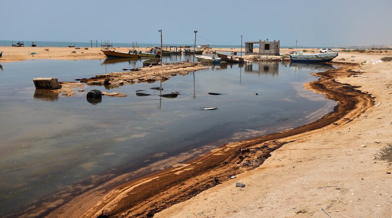 Oil residue lines the shore near fishing boats on Qeshm Island, Iran, Thursday, Aug. 13, 2026, amid ongoing wartime attacks on vessels and infrastructure in and around the Strait of Hormuz, though the spill's source has not been independently determined.(Amirhosein Khorgooi/ISNA via AP)
