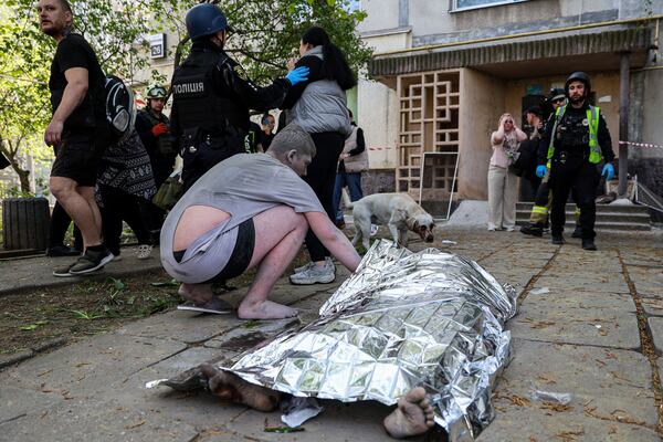 A man checks the dead body of his neighbour near a multi-storey building damaged by a Russian strike on residential neighbourhood in Zaporizhzhia, Ukraine, on Tuesday, April 22, 2025. (AP Photo/Kateryna Klochko)