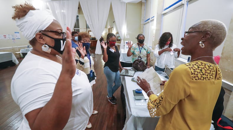 Poll manager, Raphillia Edwards, right, swears in her poll worker team Tuesday at Park Tavern in Atlanta. JOHN SPINK/JSPINK@AJC.COM