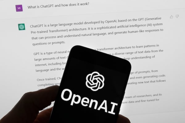 FILE - The OpenAI logo is seen on a mobile phone in front of a computer screen which displays output from ChatGPT, March 21, 2023, in Boston. (AP Photo/Michael Dwyer, File)