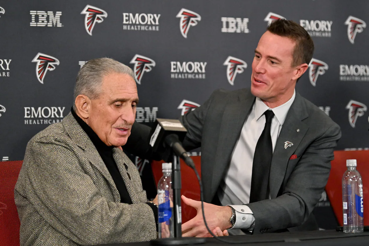 Matt Ryan holds a hand of Atlanta Falcons owner Arthur M. Blank during a news conference to introduce Ryan as the new Falcons president of football, Tuesday, Jan. 13, 2026, in Flowery Branch. (Hyosub Shin/AJC)