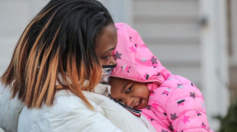 January 28, 2021 DeKalb County: Ashlee Johnson holds her 1-year-old girl,  Aasha “Cupcake” Johnson who was rescued Thursday morning, Jan. 28, 2021 after a tree fell on her bedroom, breaking through the ceiling just feet above her crib. The tree ripped through the roof and brought down drywall at the home on Scarborough Lane in DeKalb County, the child’s mother told The Atlanta Journal-Constitution. Ashlee Johnson said she was forced to watch the room crumble as she waited for help to arrive. “I was terrified,” she said. “I just thought ‘that tree is going to fall on my baby.’ That’s all I was thinking.” Johnson said she was startled awake about 6 a.m. by a loud “boom.” When she opened her eyes, she saw insulation and wood falling around her. Johnson said her 4-year-old son, Amias “Ace” Johnson was in bed with her at the time. “So I jump up, I look at him, and he’s OK,” she said. Johnson then rushed to the bedroom where her toddler, Aasha “Cupcake” Johnson, had been sleeping. Insulation and drywall littered the hallway leading to Cupcake’s room. “That’s when I noticed it was a tree,” Johnson said. “Before I thought maybe it had just rained all night and the roof caved in. I realized it was a tree when I got to her room.” Heavy rain and storms earlier in the week have left much of metro Atlanta soaked. Since Monday, DeKalb-Peachtree Airport has recorded about 2 inches of rainfall. Johnson began shoving on the door to Cupcake’s room, but it wouldn’t budge. She finally pushed the door open enough to see that the massive tree was blocking access to her daughter. Johnson said through the crack in the doorway, she could see that the walls of her child’s room were still crumbling. Part of the tree had torn through a wall above Cupcake’s crib, she said. Johnson stopped pushing the door out of fear that shoving it any further would cause it to come crashing down. “I’m watching the hole get bigger and it’s literal
