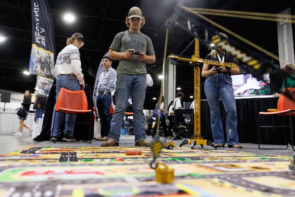 Erik Bate uses a heavy equipment toy with a controller while his brother competes in the SkillsUSA National Leadership and Skills Conference in Atlanta at the Georgia World Congress Center, Thursday, June 4, 2026. (Estela Muñoz/AJC)